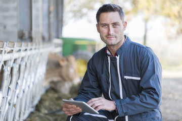 Farmer in barn using digital tablet