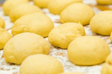 Fototapeta na wymiar Raw donuts lying in flour on wooden table