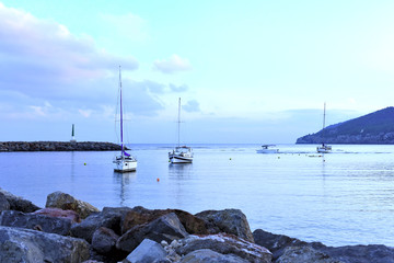 Harbor scene or sea scene with anchored boats at blue hour.