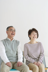 Obraz premium 椅子に座り微笑むシニア夫婦