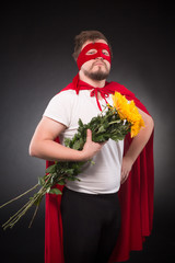 Valentine's Day concept. Picture of super hero man posing with bunch of flowers for his lovely girl isolated on black background in studio.