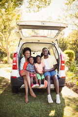 Happy family sitting on their car