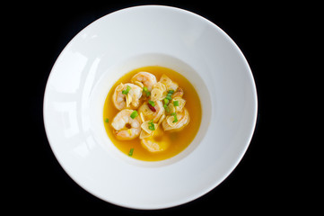 soup with shrimps and vegetables in white plate and black background