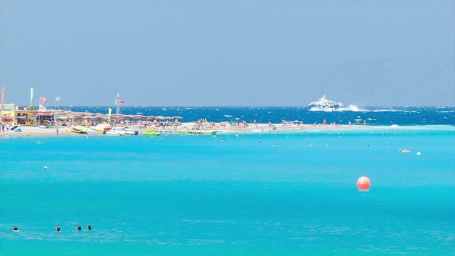 Blue Mediterranean at Eli Beach Resort in Rhodes Greece with Beachfront Activities and People Swimming in Vibrant Blue Aegean Sea Water