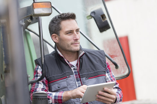 Farmer Leaning On The Tractor Using A Digital Tablet