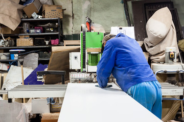 Worker using filler machine to make furniture at carpenters work