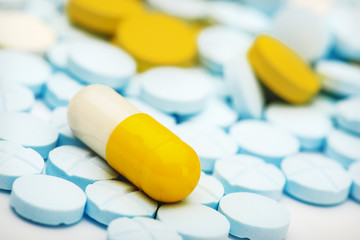 white yellow pill on a pile of medical pills
