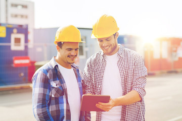 smiling builders in hardhats with tablet pc