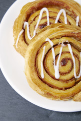A close up of a plate of freshly baked cinnamon swirls on a rustic slate background