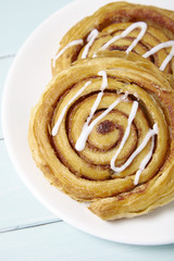A close up of a plate of freshly baked cinnamon swirls on a painted wooden table background