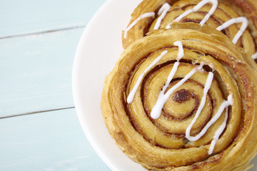 A plate of freshly baked cinnamon swirls on a painted wooden table background