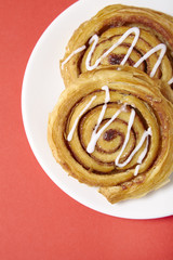 A close up of a plate of freshly baked cinnamon swirls on a bright red background
