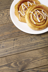 A plate of freshly baked cinnamon swirls on a rustic wooden table top background with blank space...