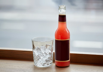 bottle of lemonade and glass with ice on table