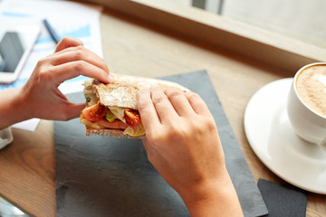 woman eating salmon panini sandwich at restaurant
