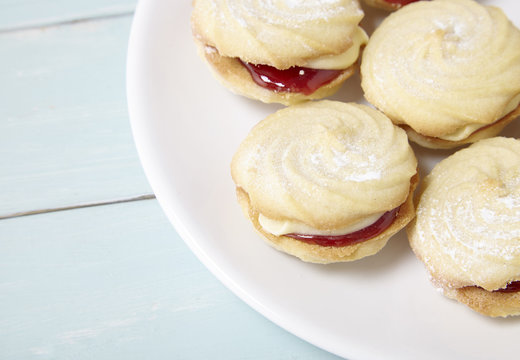 A Plate Full Of Freshly Baked Viennese Whirl Biscuits On A Blue Wooden Table Top Background