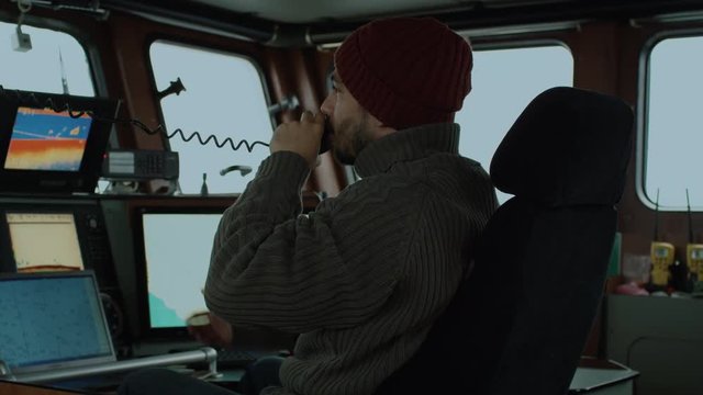 Captain of Commercial Fishing Ship Surrounded by Monitors and Screens Working with Sea Maps in his Cabin. Shot on RED Cinema Camera in 4K (UHD). 