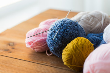 knitting needles and balls of yarn on wood