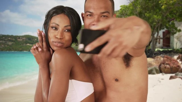 Black couple on honeymoon taking selfie on Caribbean beach