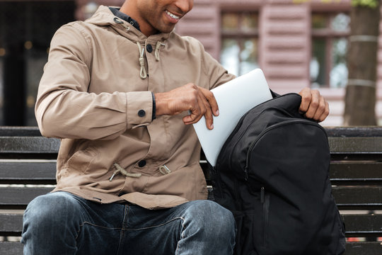 Cropped Photo Of African Man Getting Laptop From Backpack