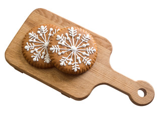 Fototapeta na wymiar Gingerbread with snowflakes of the glaze. Sweets for Christmas. Two sticks on a wooden board.