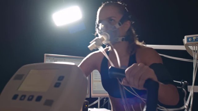 Tilt down of strong determined female athlete cycling exercise bike during cardiopulmonary testing in lab