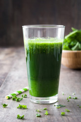 Kale smoothie in glass on wooden background.
