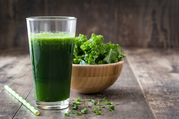 Kale smoothie in glass on wooden background.
