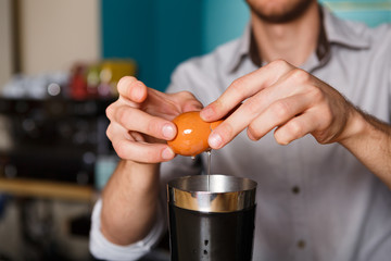 Barman's hands making cocktail with egg yolk