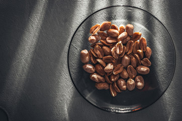 Roasted salted peanuts in plate on old wooden table