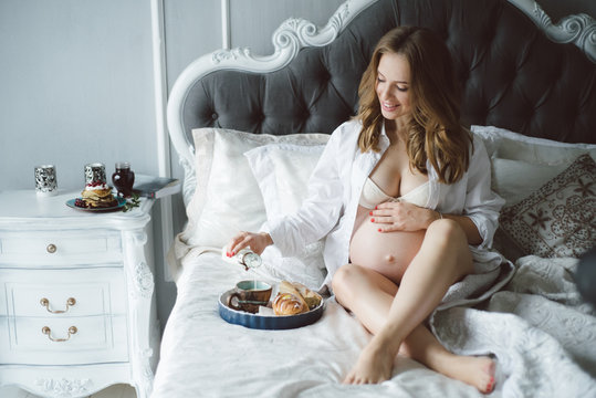 Breakfast in bed and young pregnant beautiful girl