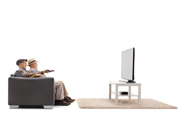 Two mature men sitting on a sofa and watching television