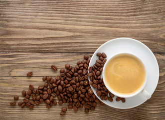 White coffee cup and beans on old wooden background.