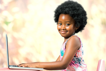 Cute afro american kid typing on laptop.