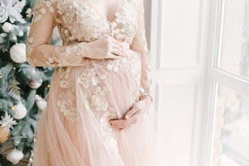Pregnant girl in dress near Christmas decorations
