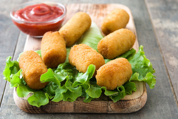 Traditional fried Spanish croquetas (croquettes) with ketchup on wooden background
