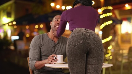 Attractive young woman flirting with boyfriend as he sits at coffee shop