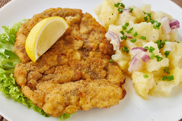 Weiner schnitzel with potato salad on a wooden background