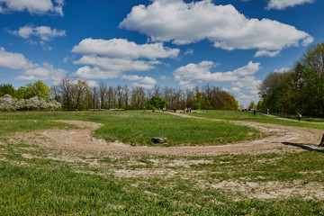 Summer landscape. The road near the forest on a background of blue sky with clouds