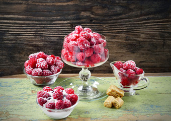 Red frozen raspberries in a glass cup on a wooden table