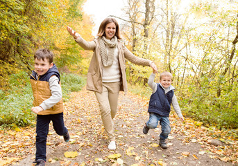 Beautiful mother with her sons in autumn forest.