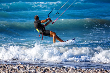 Kitesurfing. Kitesurfer rides the waves on high speed at sunset