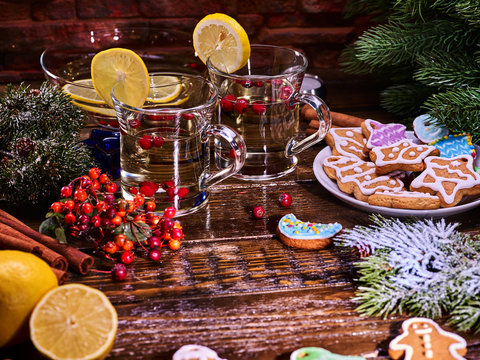 Christmas still life with pair mug decoration lemon slice hot punch on wooden table and gingerbread Cookie. Red berries on wooden table. Brick wall background.