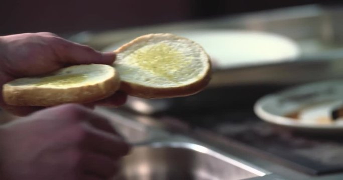 Chef making hamburger 4k video. Hand greasing burger bread bun on fast-food restaurant 