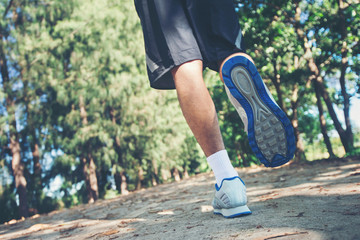 close up foot of young runner man running along road in the park