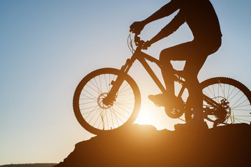 Fototapeta premium Silhouette of a man on mountain-bike during sunset.