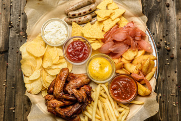 wide selection of snacks for beer with different sauces on parchment top view