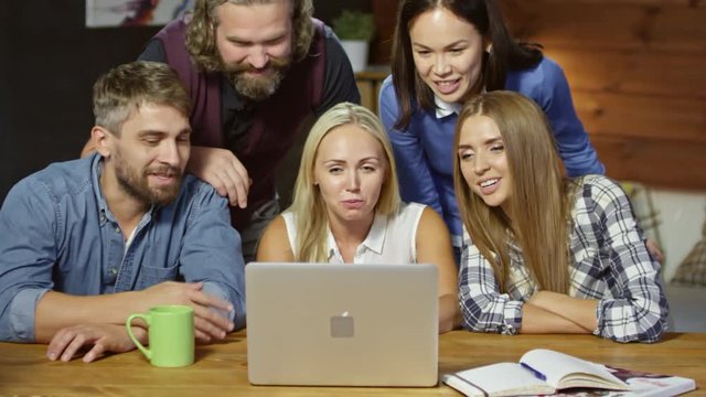Group of young people smiling and laughing while speaking via video call on computer at home