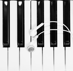 Naklejka premium earphones on piano keys, black and white