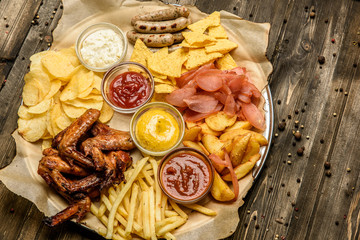 wide selection of snacks for beer with different sauces on parchment top view